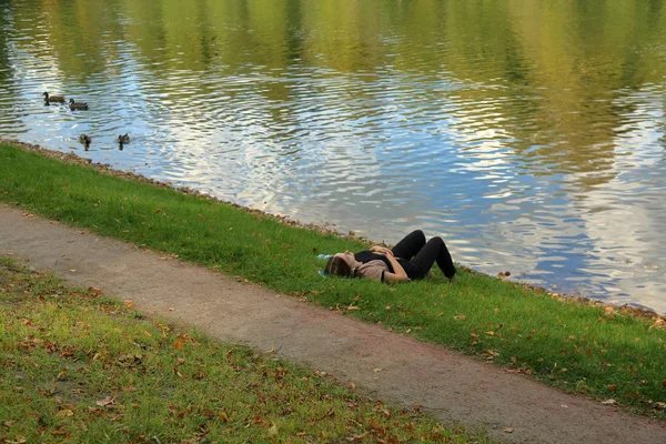 Jovem está relaxando na margem de um lago tranquilo — Fotografia de Stock