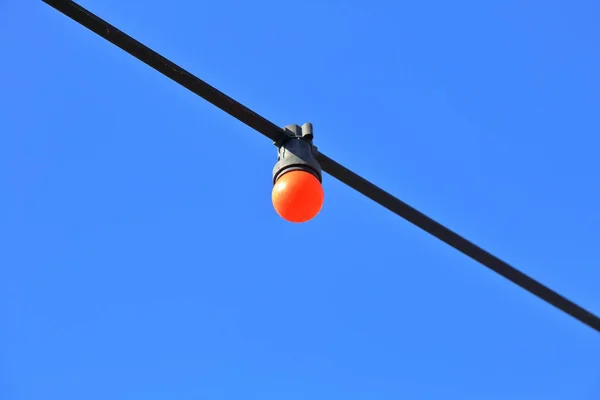 Colored street lamp without lampshade on a wire — Stock Photo, Image