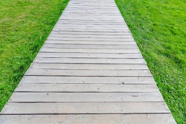 Modern yeşil şehir parkında yürüyen yayalar için tahtadan yapılmış bir patika.