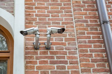 Eski bir binanın duvarındaki açık hava güvenlik kamerası.