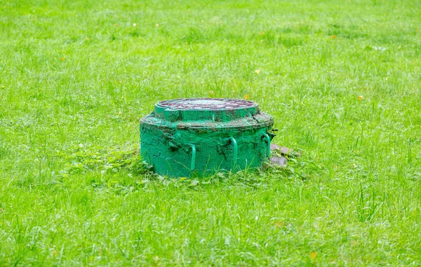 緑豊かな緑の草の間の古い丸マンホール — ストック写真