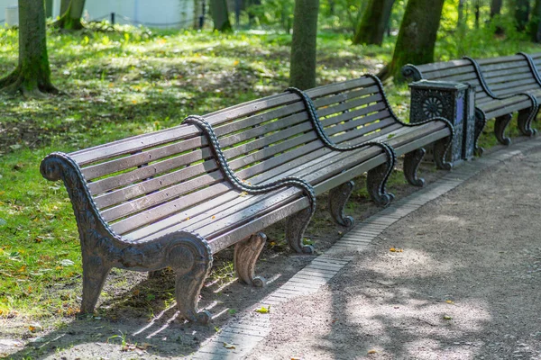 Yazın bir şehir parkında levhalardan ve demirden yapılmış bir bank.