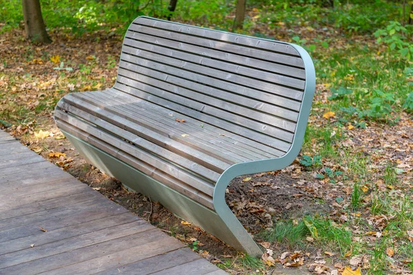 秋天在一个城市公园里用木板和锻铁做的休闲长椅 — 图库照片