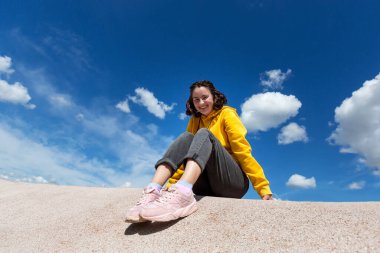 Atletik güzel genç, mavi gökyüzüne karşı oyun bahçesinde oturuyor..