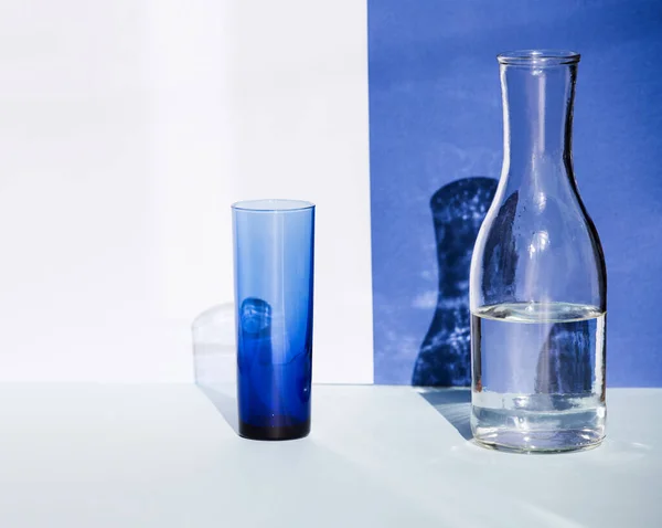Gelas biru transparan dan botol air di bawah sinar matahari. — Stok Foto
