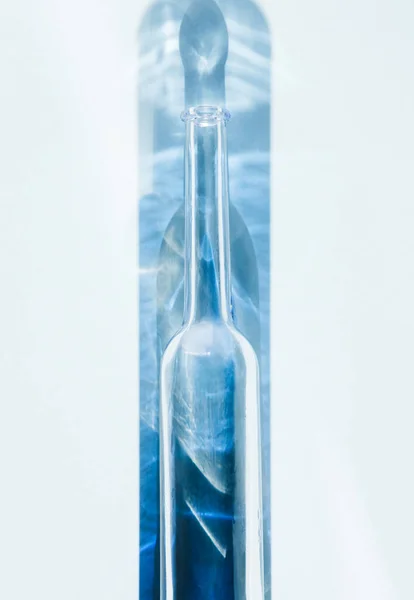Transparente Flasche und Schatten. Sonnenlicht und Blau. — Stockfoto
