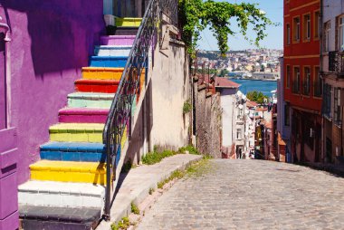 İstanbul 'un Balat ilçesinde açık manzaralı, mor bir duvarın kenarına parlak renklerle boyanmış bir merdiven..