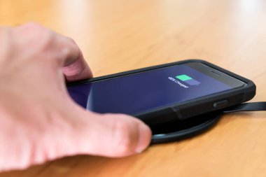Erkekler akıllı telefonu kablosuz pille şarj ediyorlar. Yeni teknoloji cep telefonunu kablo şarj cihazı ya da tümevarımsal şarj olmadan şarj edebiliyor..