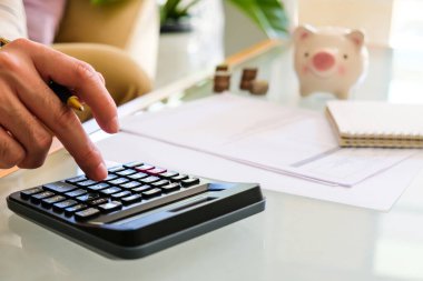 Asyalı erkeklerin seçici odak noktası arka planda belge ve domuz kumbarası ile kişisel tasarruf hesapları yaparken.