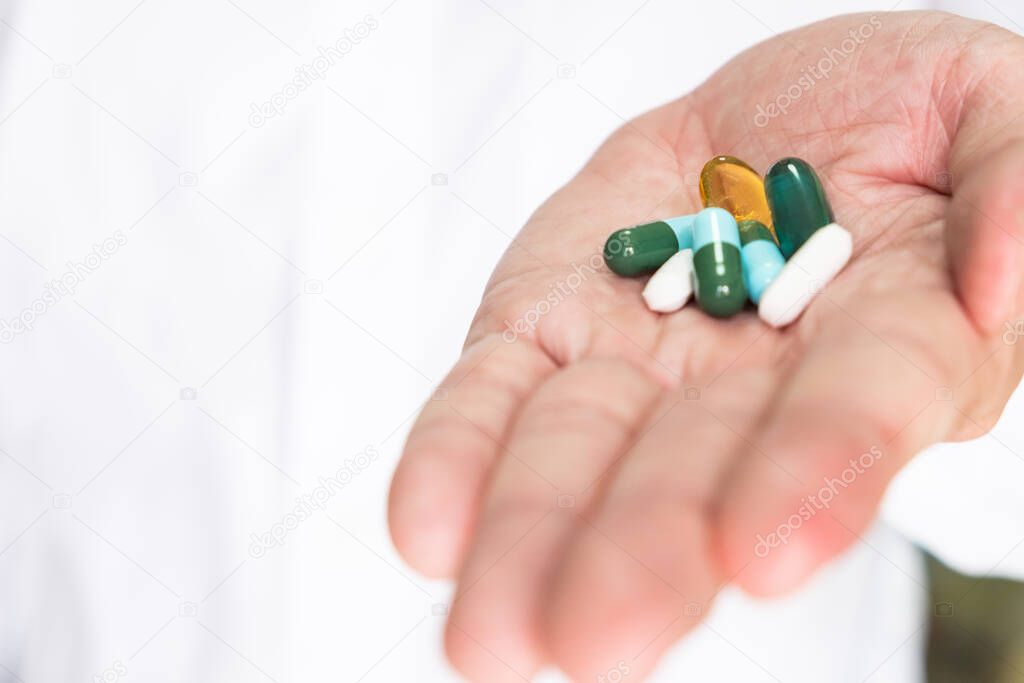 Selective focus at the medicine pills. On The doctor palm with different type of drug tablet.  Medical treatment to cure illness. Healthcare and medical concept with copy space.
