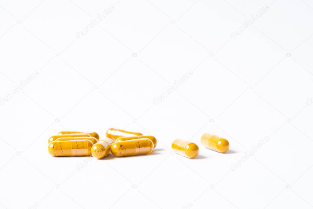 Selective focus shot of turmeric herb capsule on isolate white background. Alternative, natural healthcare product instead of using medicine.