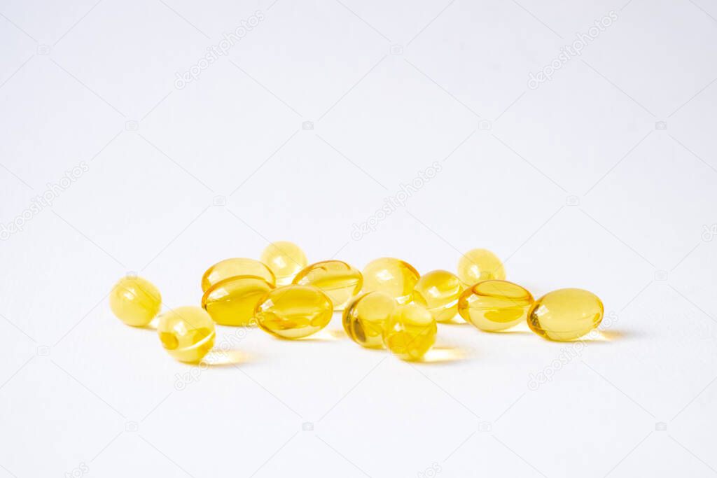 Selective focus of yellow fish oil supplement capsule on isolate white background. Medicine and vitamin for good body nutrition. Healthcare and medical concept.