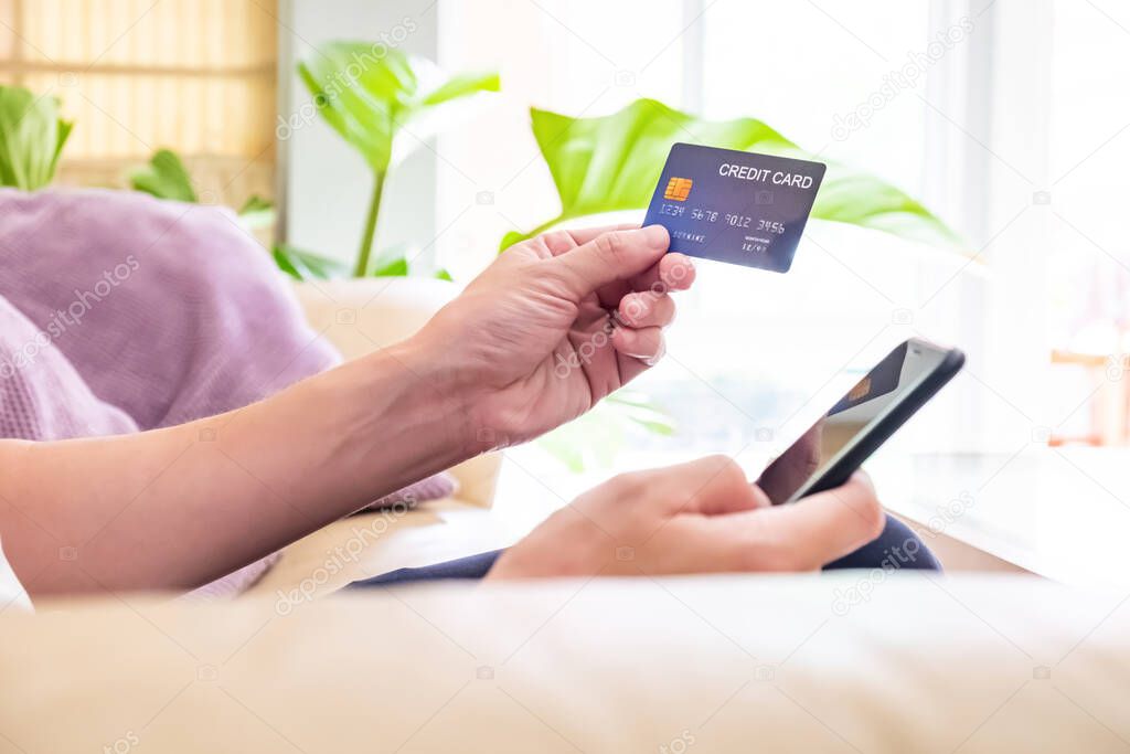Selective focus at men hand pressing purchase button on digital tablet for online shopping with blurred credit card as background. Online payment concept to support social distance.
