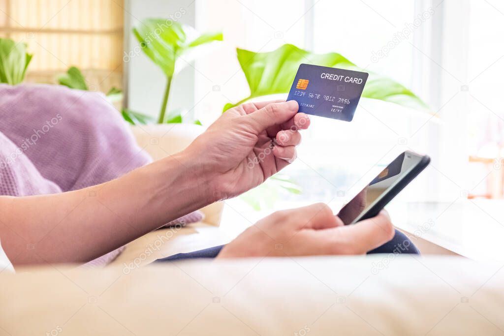 Selective focus at men hand pressing purchase button on digital tablet for online shopping with blurred credit card as background. Online payment concept to support social distance.