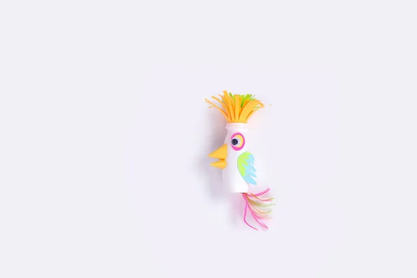 Child makes a craft from paper and recycled yogurt bottle, DIY Paper parrot. Kindergarten and school activity — Stock Photo, Image