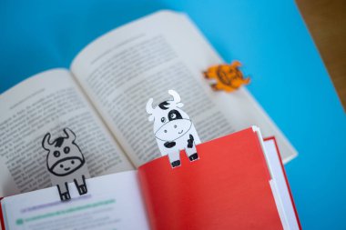 Mavi arkaplanda inek yer imleri olan kırmızı kitap