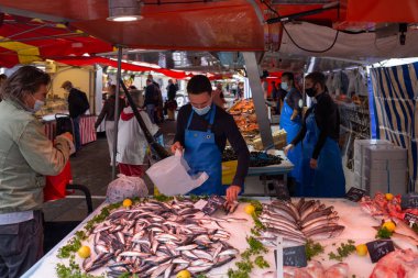 Fransa 'nın pazar yerinde alışveriş yaparken yüz maskesi takan insanlar açık havada maske takmak zorunludur.