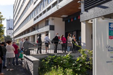 Koronavirüsü önlemek için Fransa 'daki sosyal güvenlik bürosunda sırada beklerken yüz koruyucu maske takan insanlar için dışarıda maske takmak zorunludur.,