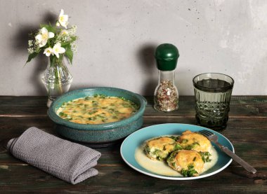 Ispanak soslu fırında köfte ve eski ahşap bir masada peynir.