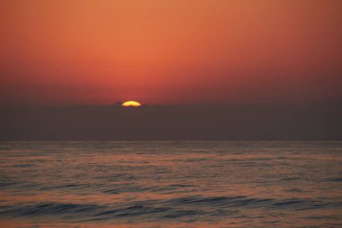 Okyanusta gün doğumu, güneş görünür. Karanlık dalgalar, yalnız, masum