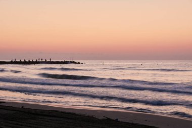 Sahilde gün doğumu, balıkçılarla iskele, uzun pozlama, renkli kum, ipek efekt
