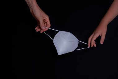 Koruyucu maskeli çocuk ve kadın eli, siyah arkaplan, Covid-19