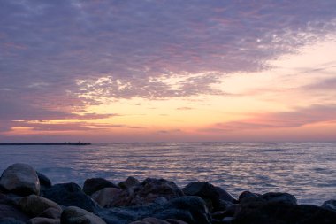 Gün doğumunda Rocky plajı, uzun pozlama, sisli bulutlar