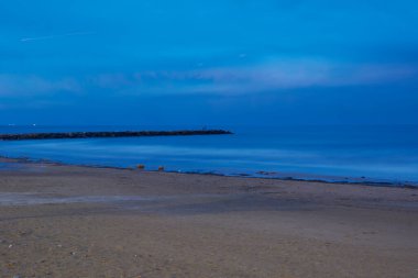 Gün batımında sahilde dalgalanma, uzun pozlama, boyama etkisi.
