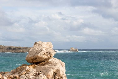 İspanya, Mallorca, Cala Ratjada sahilinde kayalar ve fırtınalı Akdeniz. Bulutlar ve dalgalar.
