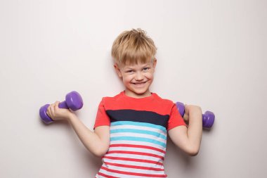 Beyaz arka plan üzerinde dambıllı çocuk. Stüdyo portresi