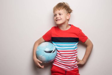 Sevimli küçük çocuk futbol topu ile ayakta ve kamera bakıyor. Beyaz üzerine izole edilmiş. Stüdyo portresi