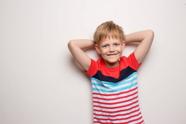 Beyaz arka planda izole edilmiş tişörtlü küçük gülümseyen çocuk. Stüdyo portresi