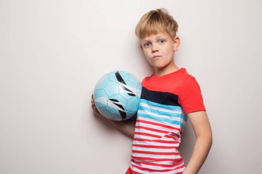 Sevimli küçük çocuk futbol topu ile ayakta ve kamera bakıyor. Beyaz üzerine izole edilmiş. Stüdyo portresi