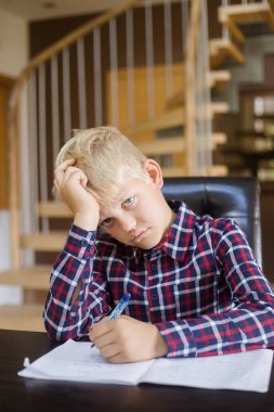 Üzgün bir öğrenci evde not defterine yazıyor. Ödev. Eğitim, çocukluk ve insan kavramı