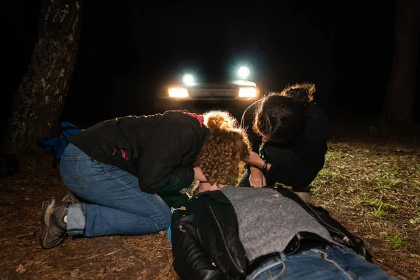 Two Women Helping Man Lying Ground Night Scene Headlights Car — Stock Photo, Image