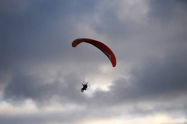 Paraglider flies in stormy skies.