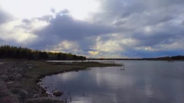 Gölün üzerinde uçan bulutlar gün batımı ışınlarına yansır. Kuzey Avrupa'nın Peyzaj Yaban Hayatı.