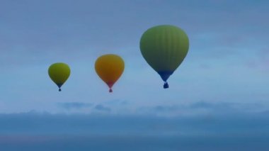 Gün batımı bulutlarında uçan balonlar.