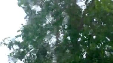 Araba penceresinin dışındaki kasırga yağmuru manzarası. Cam sileceklerin arkasında fırtınalar kopuyor..