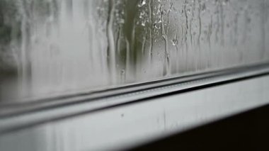 Pencereye bardaktan boşalırcasına yağmur yağıyor. Cam camlara yağmur damlaları vuruyor. Gri yağmurlu iç karartıcı manzara evin içinden.