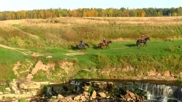 Всадники на лошадях по живописным холмам возле водопада. — стоковое видео