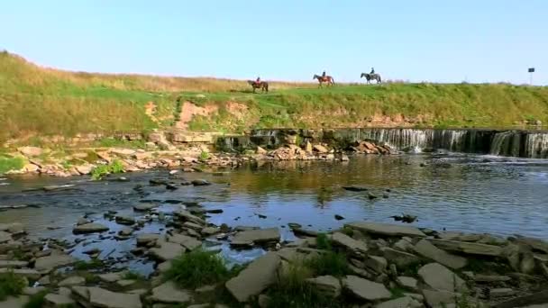 Jinetes a caballo por las pintorescas colinas cerca de la cascada. — Vídeos de Stock