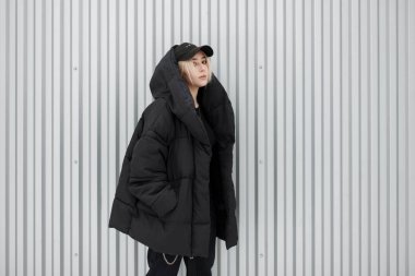 Siyah kış ceket metal duvarın yanında bir moda siyah kapaklı şık güzel şık genç model kız