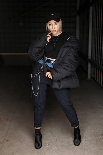 ファッショナブルなパンツと靴でキャップと黒のファッション冬ジャケットの美しい若い流行女性 — ストック写真