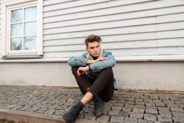 bir kot moda ceket siyah pantolon ve bir ahşap evin oturan ayakkabı ile şık şık genç adam