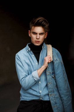 Genç yakışıklı olan saç modeli şık moda denim giysileri ile sokakta poz bir kot pantolon ile