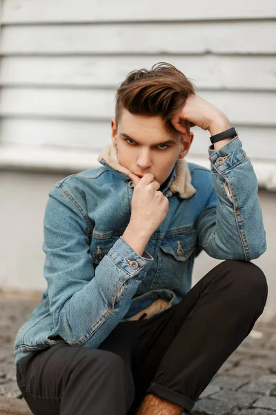 ファッション ジーンズのジャケットを木製の壁の近くで散髪の若い男のスタイリッシュなおしゃれなポートレート — ストック写真