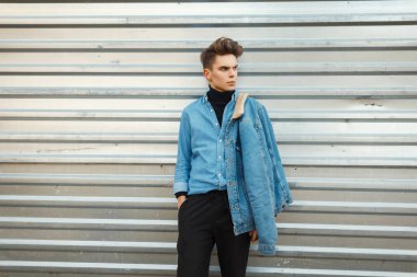 Yakışıklı genç bir model bir kot moda gömlek bir metal duvar sokak yakınındaki poz bir moda kot ceket