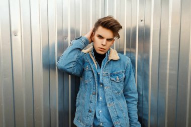 Moda şık bir saç modeli şık denim ceket ve gömlek metal duvarın yanında adamla