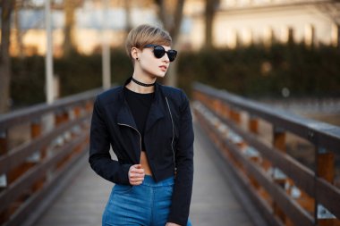 Genç kadında moda: açık havada yürüyüş kot ile siyah ceketli siyah güneş gözlüğü